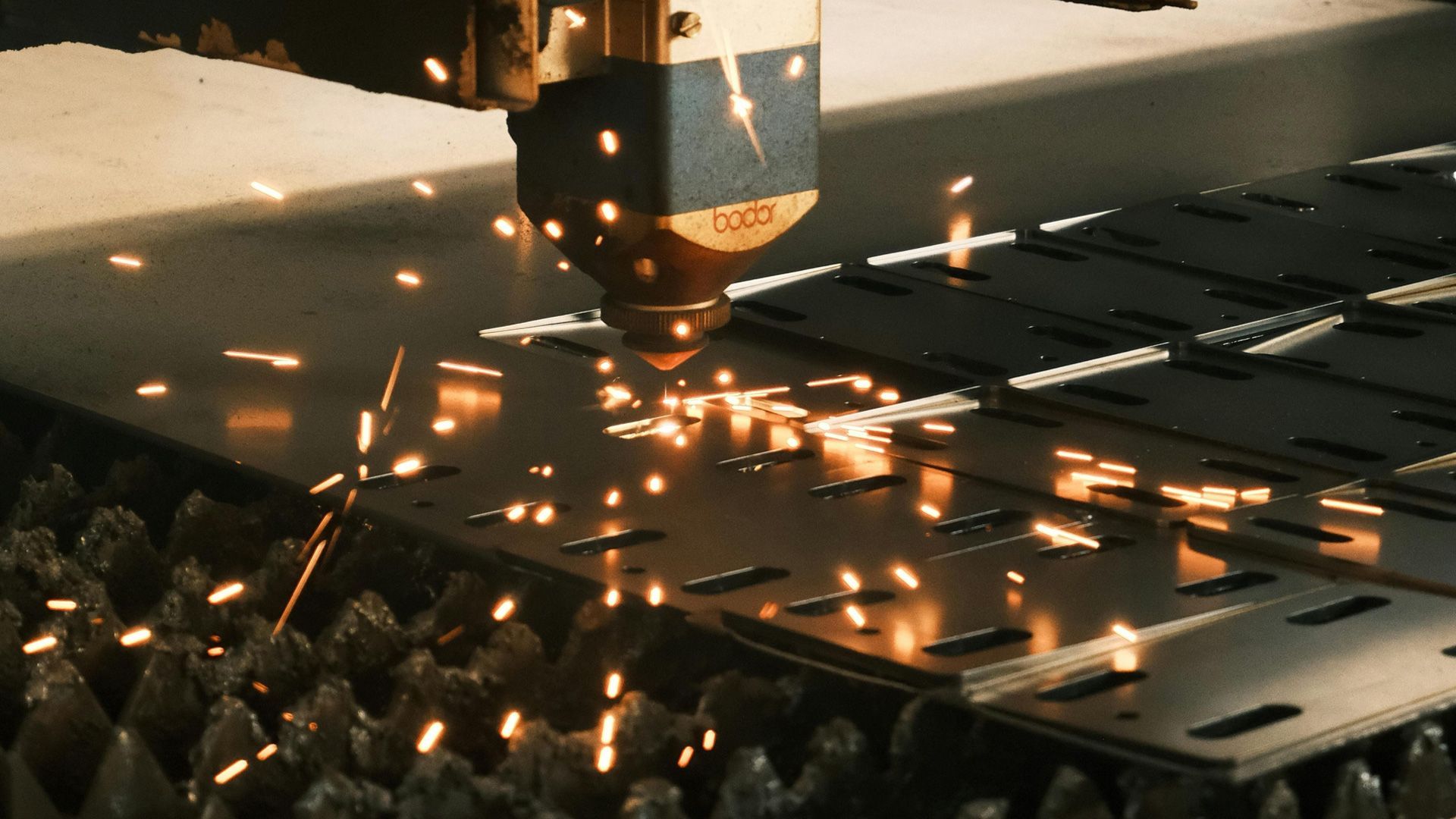 Laser cutting sparks off a sheet of metal during fabrication