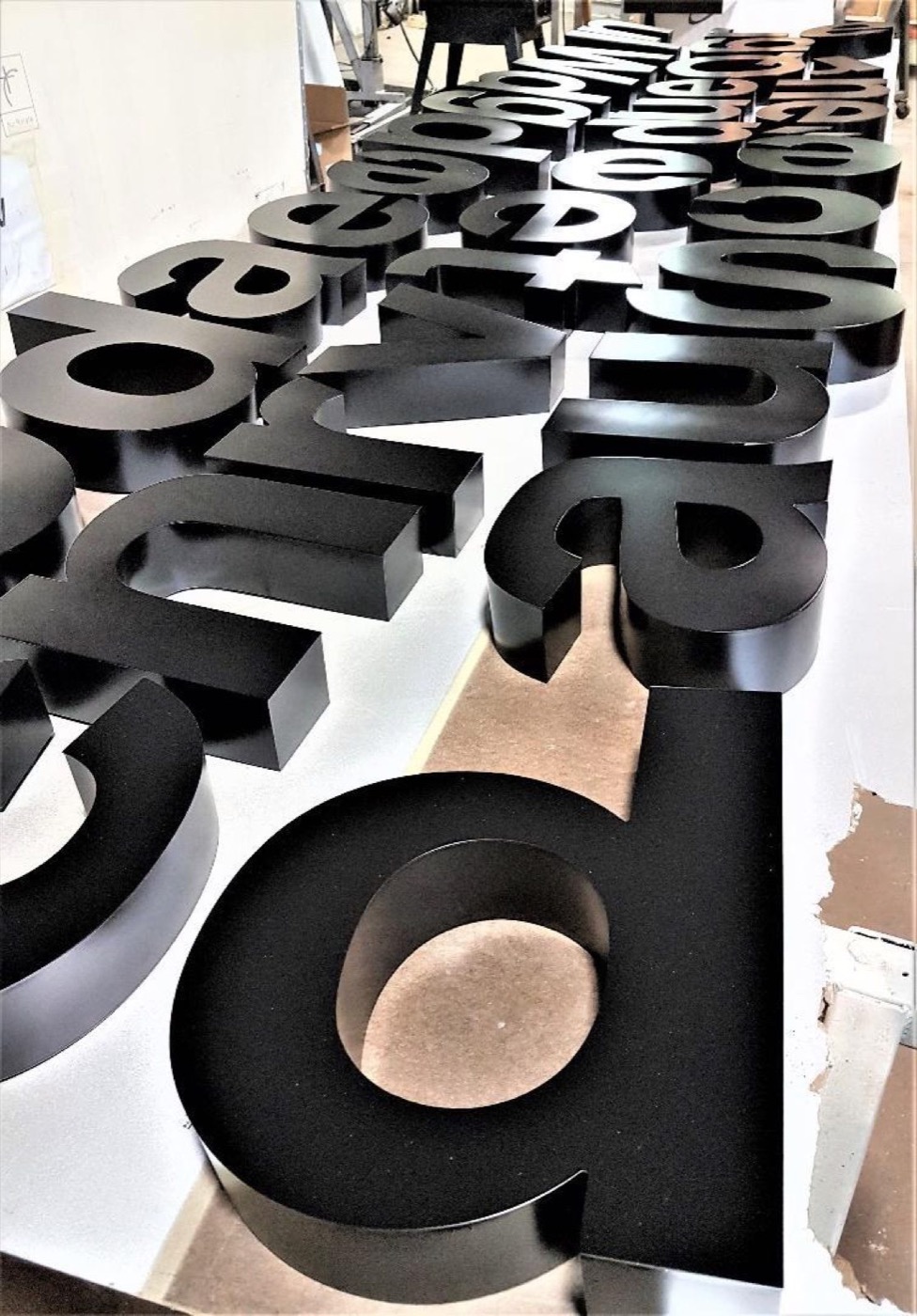 Fabricated channel letters spelling a brand name, staged on a production table before finishing